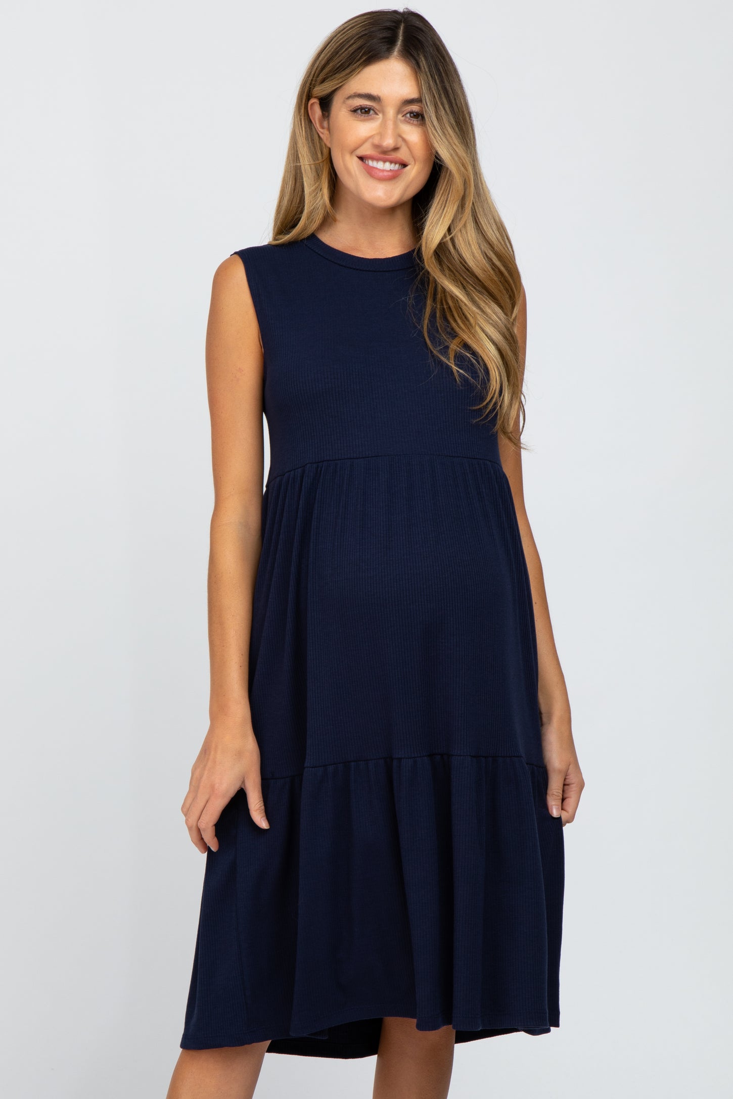 woman wearing a navy blue sleeveless maternity dress with a tiered skirt and visible baby bump