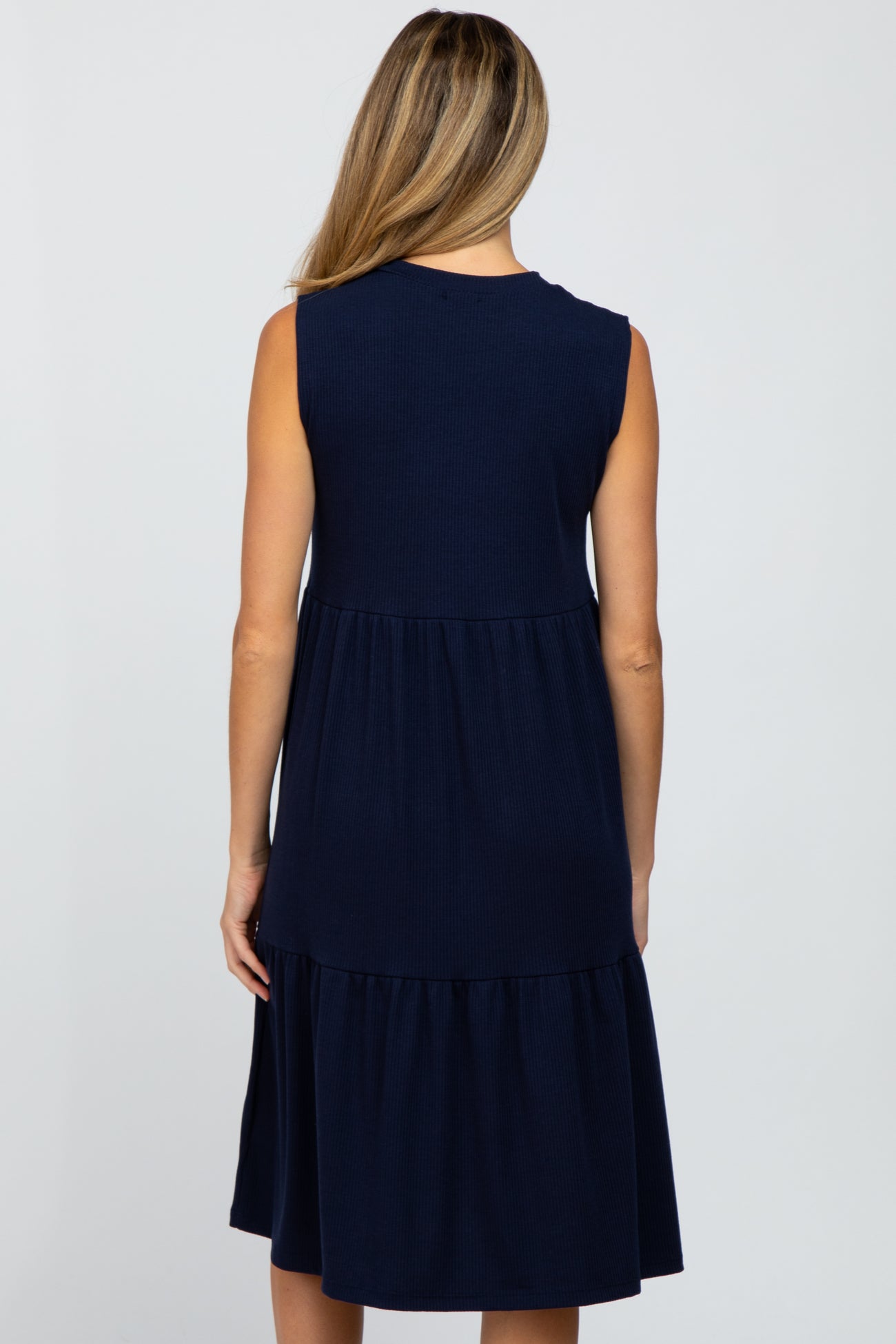 woman wearing a navy blue sleeveless maternity dress with a tiered skirt and back view displayed