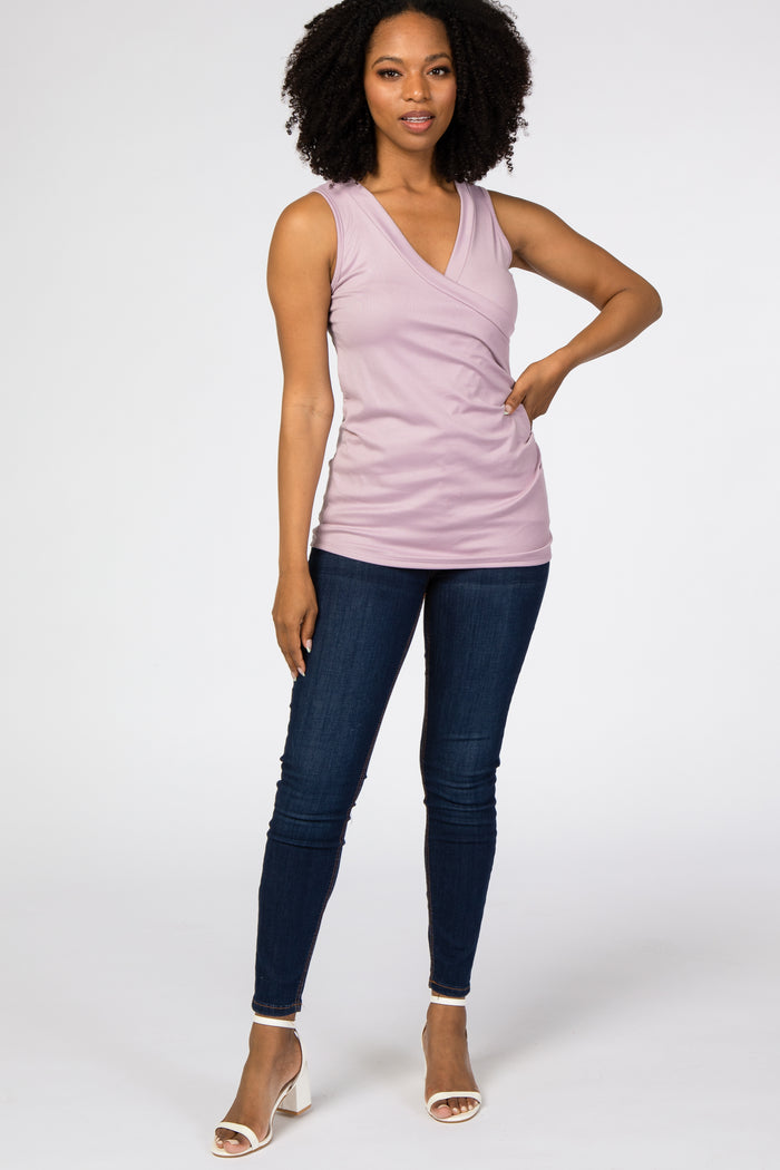 woman wearing a lavender sleeveless wrap top with a v-neckline and high-waisted dark jeans