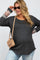 woman wearing a dark gray maternity top with leopard print details on the sleeves and a visible baby bump