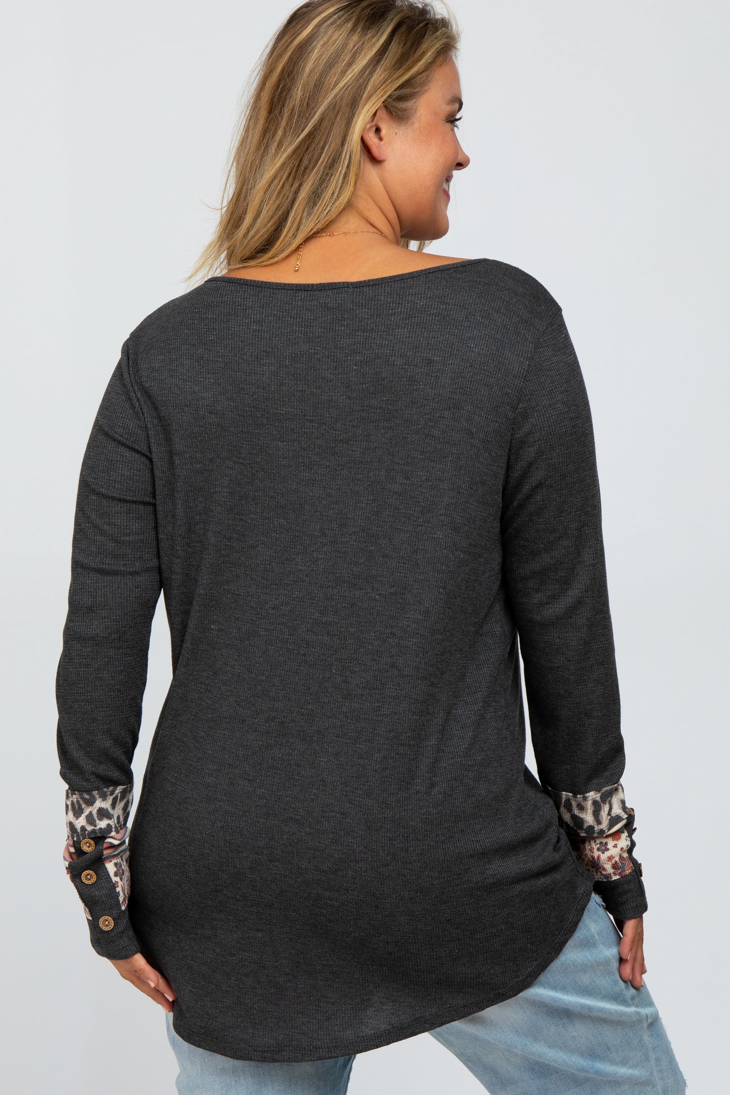 woman wearing a dark gray maternity plus top with leopard print detail on the sleeves and a relaxed fit