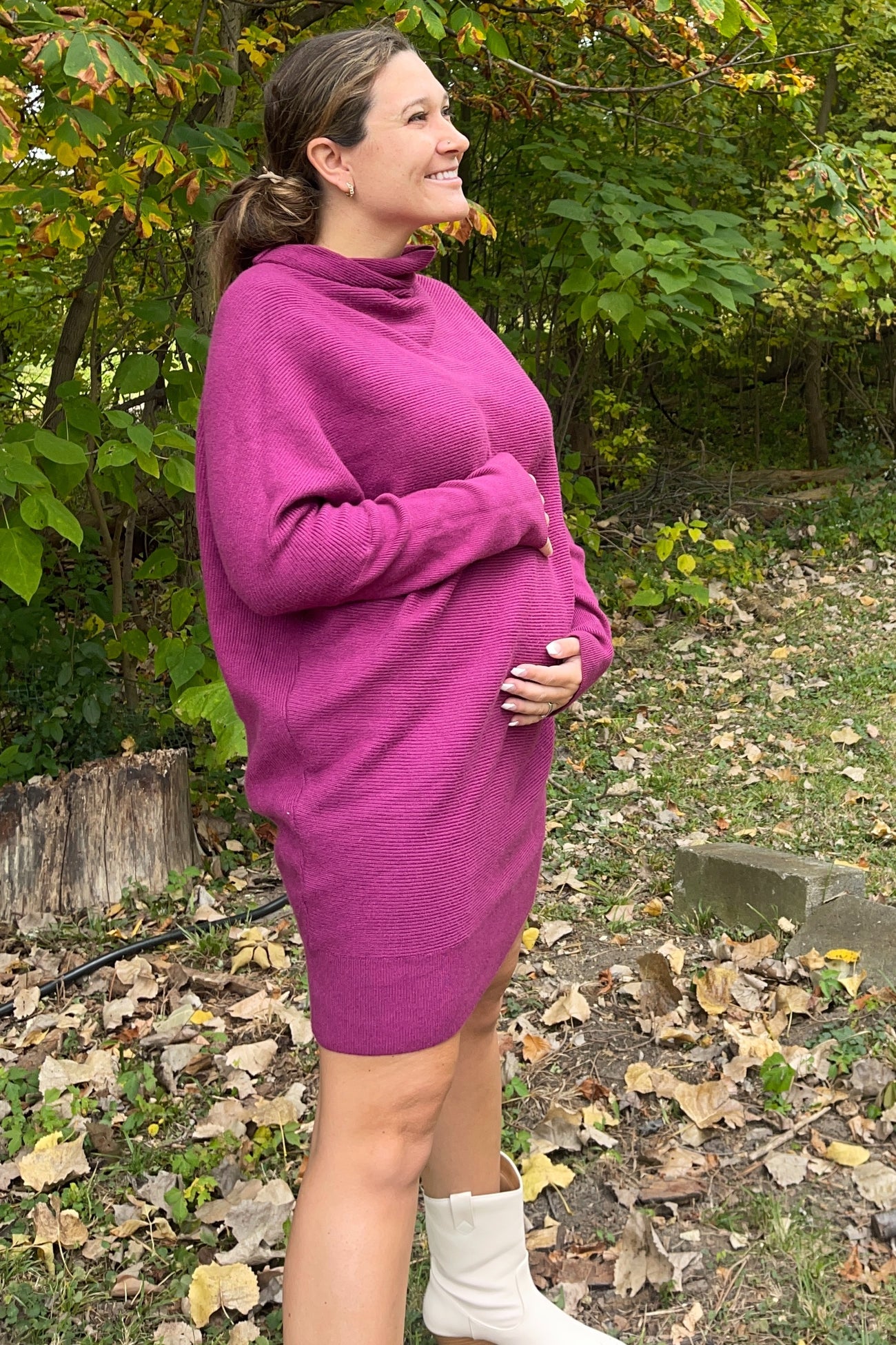 woman wearing a vibrant purple oversized maternity sweater dress and holding her baby bump