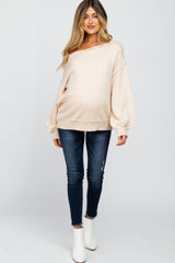 pregnant woman wearing a cream off-the-shoulder maternity sweater and dark wash skinny jeans