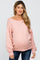 woman wearing a light pink maternity sweater with a loose fit and long sleeves, showcasing her baby bump