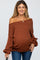 woman wearing a rust off-the-shoulder maternity sweater with a visible baby bump, holding a black umbrella