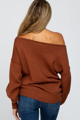 woman wearing a rust-colored off-the-shoulder maternity sweater with relaxed fit and long sleeves