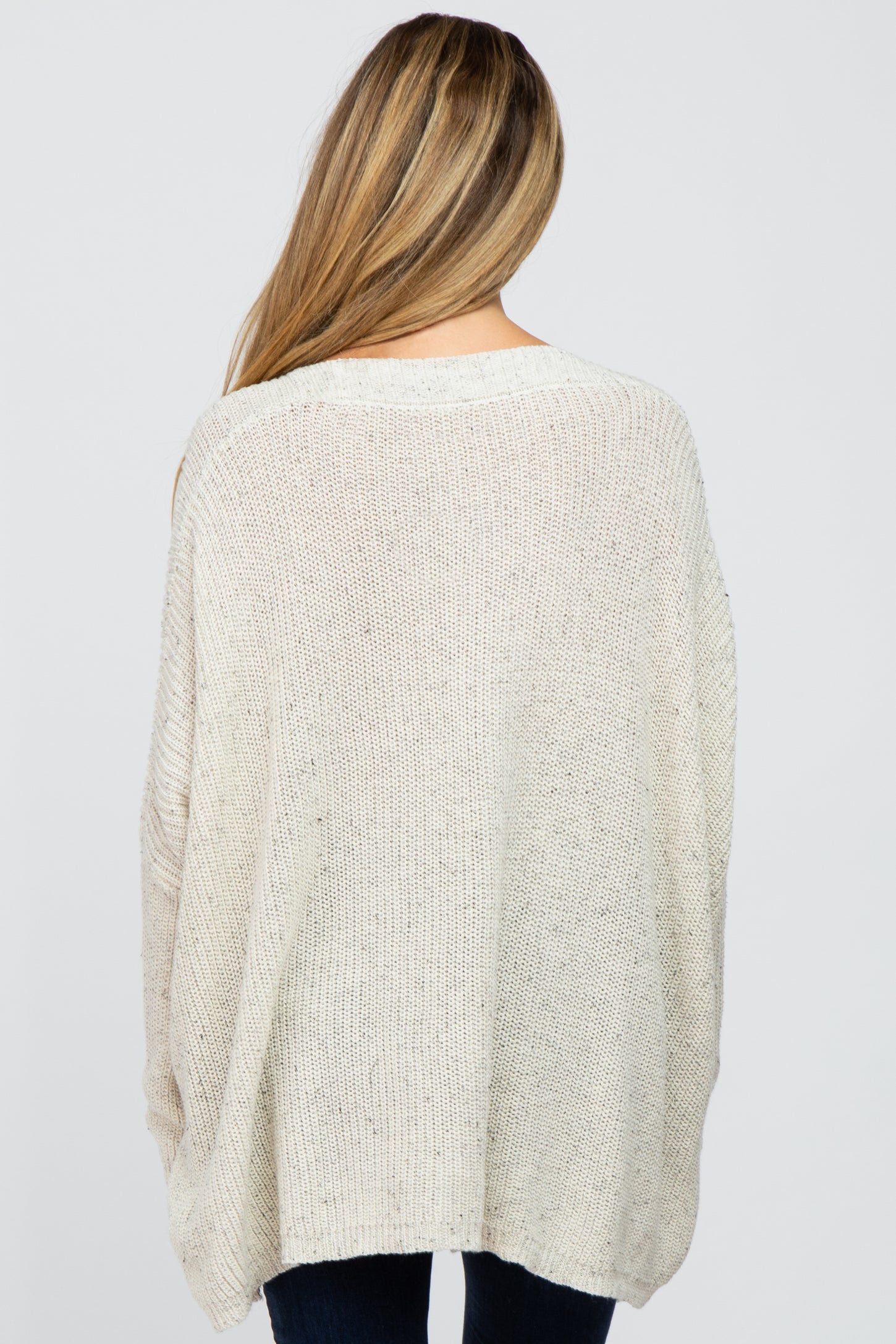 woman wearing a cream oversized maternity knit sweater, showing the back view with a relaxed fit