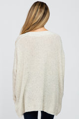 woman wearing a cream oversized maternity knit sweater, showing the back view with a relaxed fit