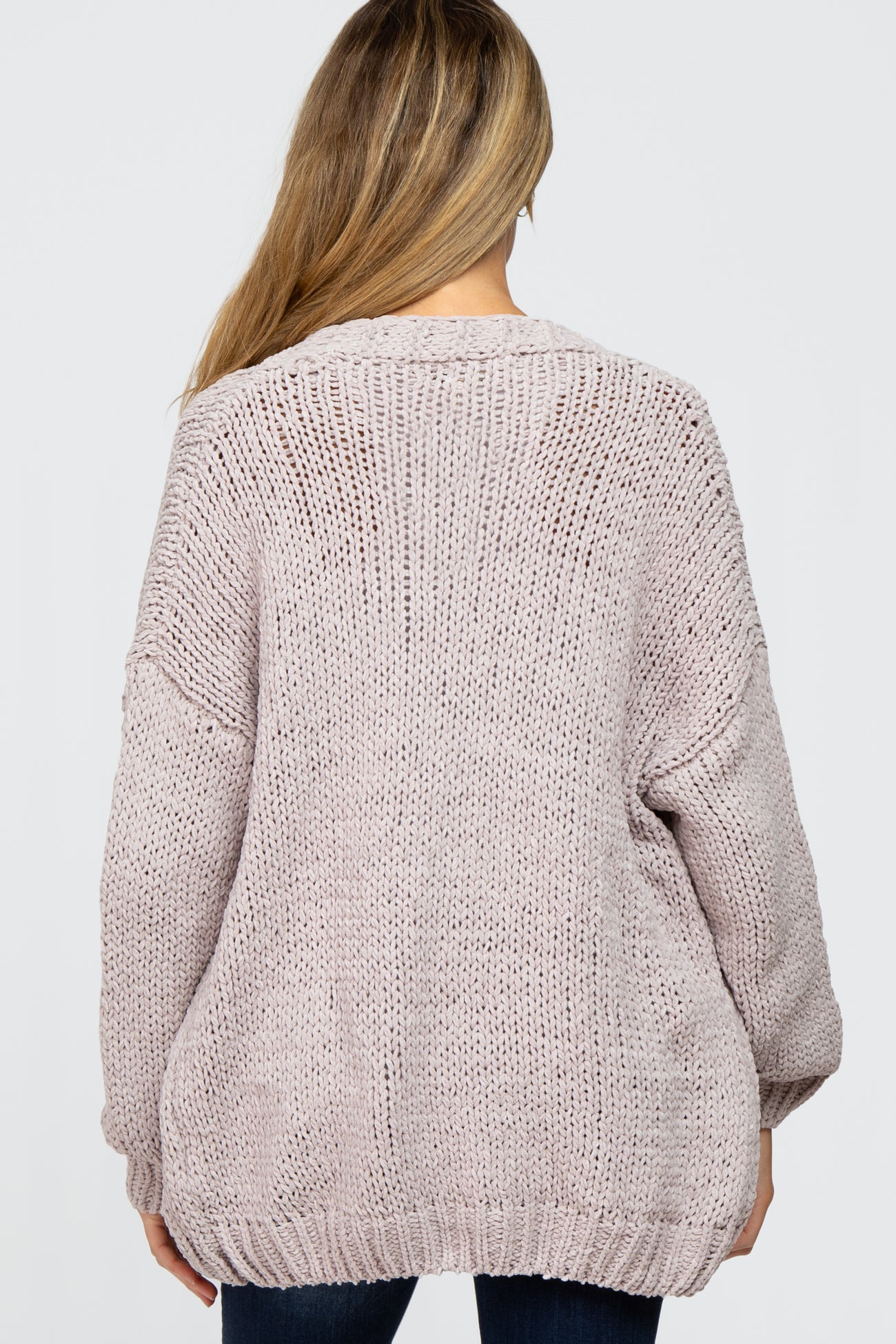 woman wearing a light pink oversized knitted maternity sweater with a loose fit, shown from the back