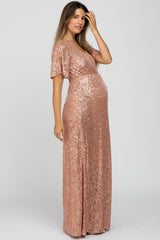 woman wearing a rose gold sequin maternity gown with short sleeves and a stylish wrap design, highlighting her baby bump