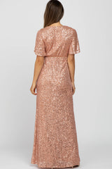 woman wearing a rose gold sequin maternity maxi dress with short sleeves and a fitted waistline