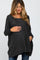 woman wearing a dark gray oversized maternity sweater and cradling her baby bump