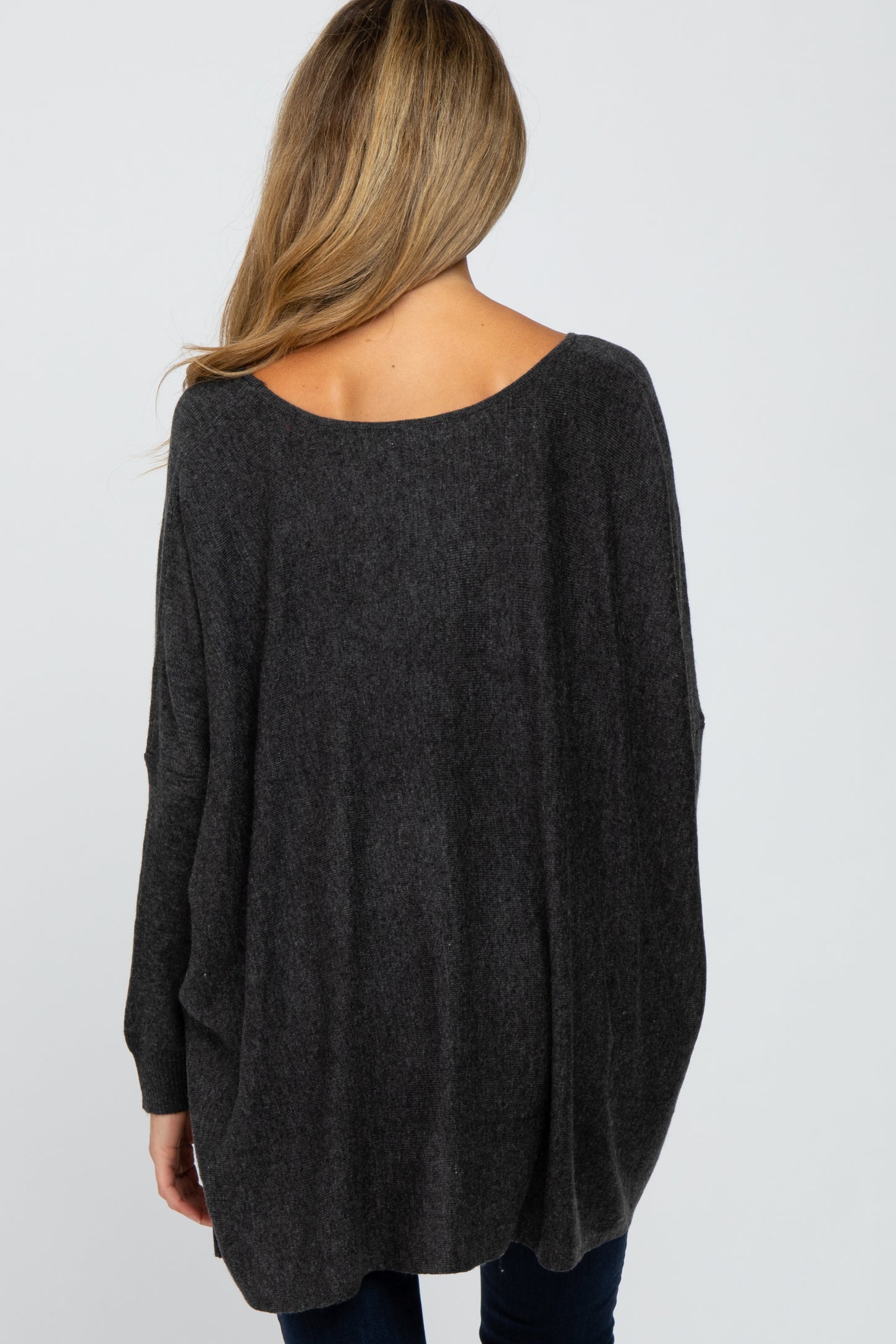 woman wearing a dark grey oversized maternity sweater, showing a relaxed fit and boat neckline from the back