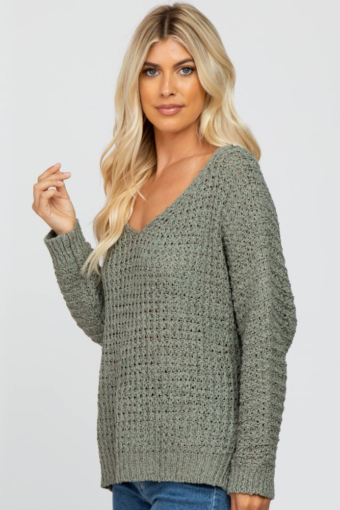 woman wearing a green v-neck knitted sweater with a relaxed fit and long sleeves