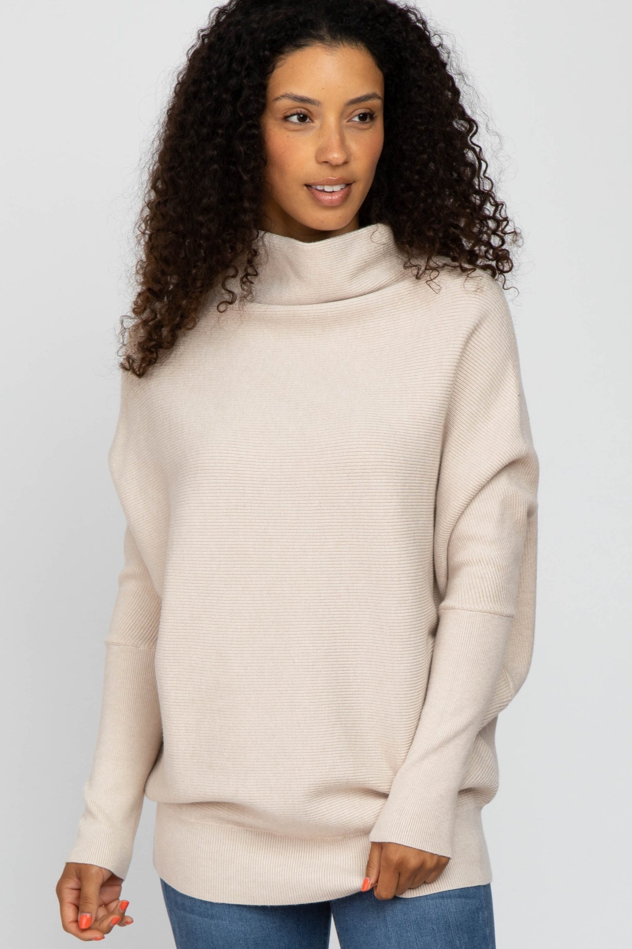 woman wearing a beige oversized turtleneck sweater with long sleeves and a relaxed fit