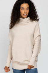 woman wearing a beige oversized turtleneck sweater with long sleeves and a relaxed fit