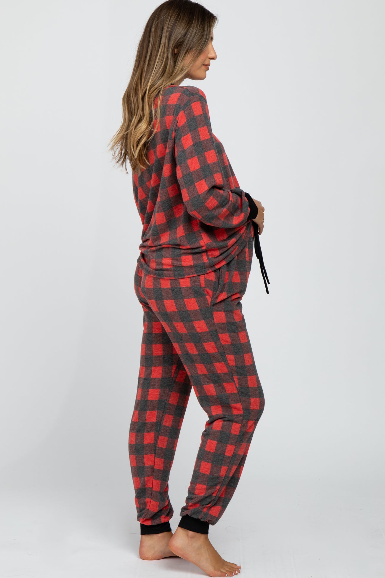 woman wearing a red and black plaid maternity pajama set with long sleeves and pants, showing her baby bump