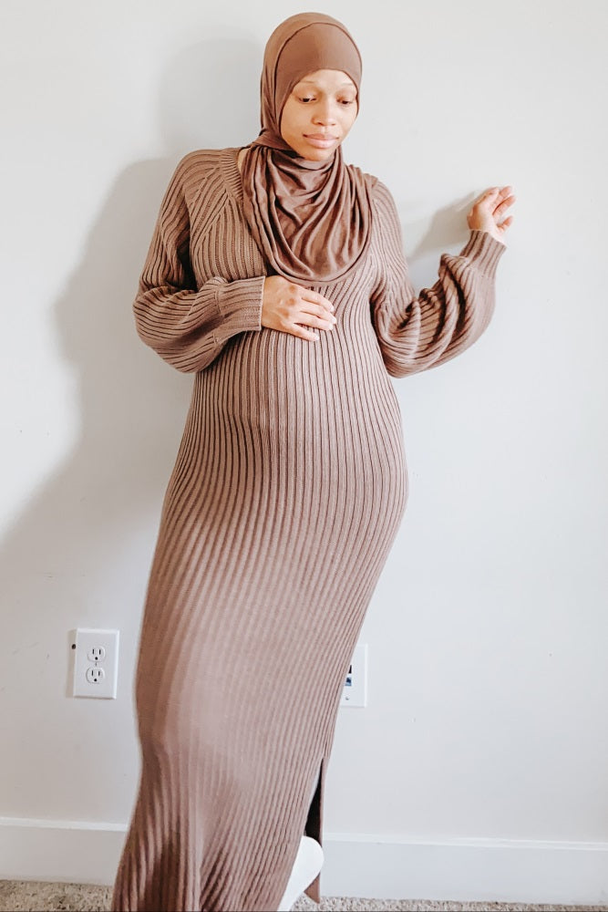 woman wearing a brown ribbed maternity maxi dress and a matching headscarf, showing her baby bump