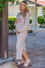 woman wearing a beige ribbed maternity dress with side slits and holding her baby bump