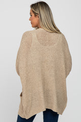 woman wearing a beige loose knit maternity cardigan, viewed from the back, showing its relaxed fit