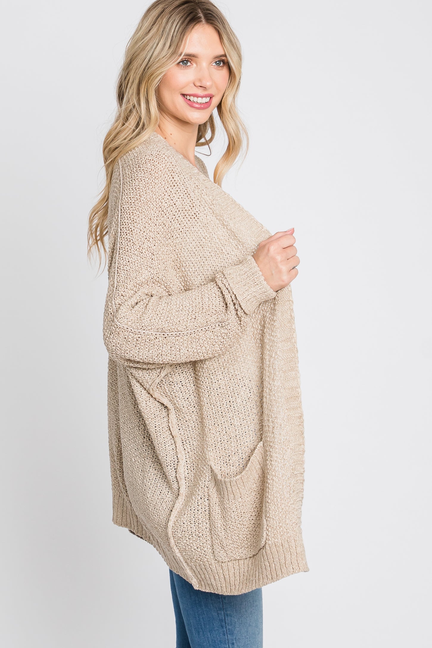 woman wearing a beige oversized cardigan with pockets, styled casually over a top and jeans