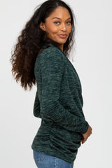 woman wearing a dark green long sleeve top with a relaxed fit and side ruching detail, styled with jeans
