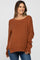 woman wearing a rust-colored oversized maternity sweater with a wide neckline and relaxed fit