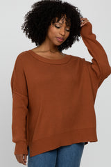 woman wearing a rust oversized sweater with a wide neckline and ribbed cuffs, paired with denim jeans