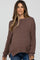 woman wearing a brown maternity sweater with a relaxed fit and side slits, showing her baby bump