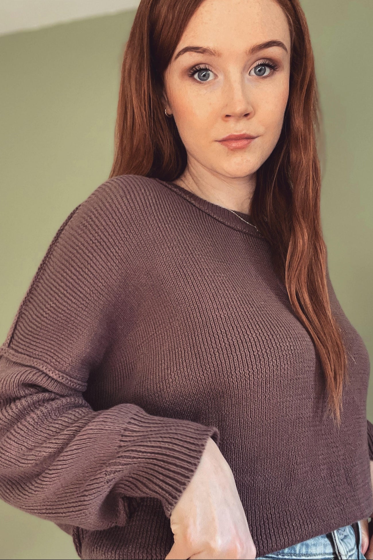 woman wearing a cropped mauve sweater with long sleeves and ribbed detailing
