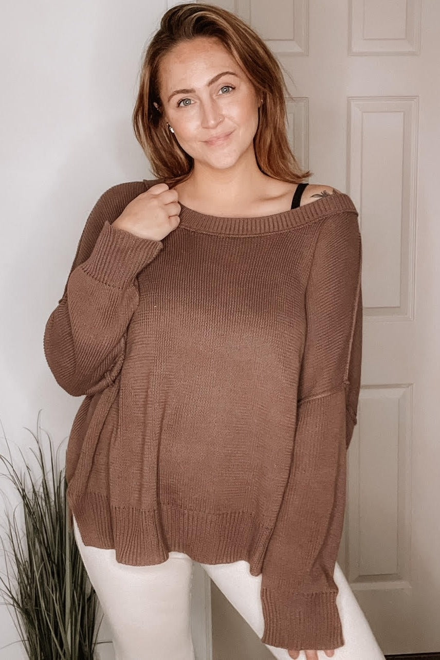 woman wearing a brown oversized sweater with off-shoulder style and light-colored pants