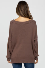 woman wearing a soft brown oversized maternity sweater, seen from the back, styled with relaxed fit and dropped shoulder seams