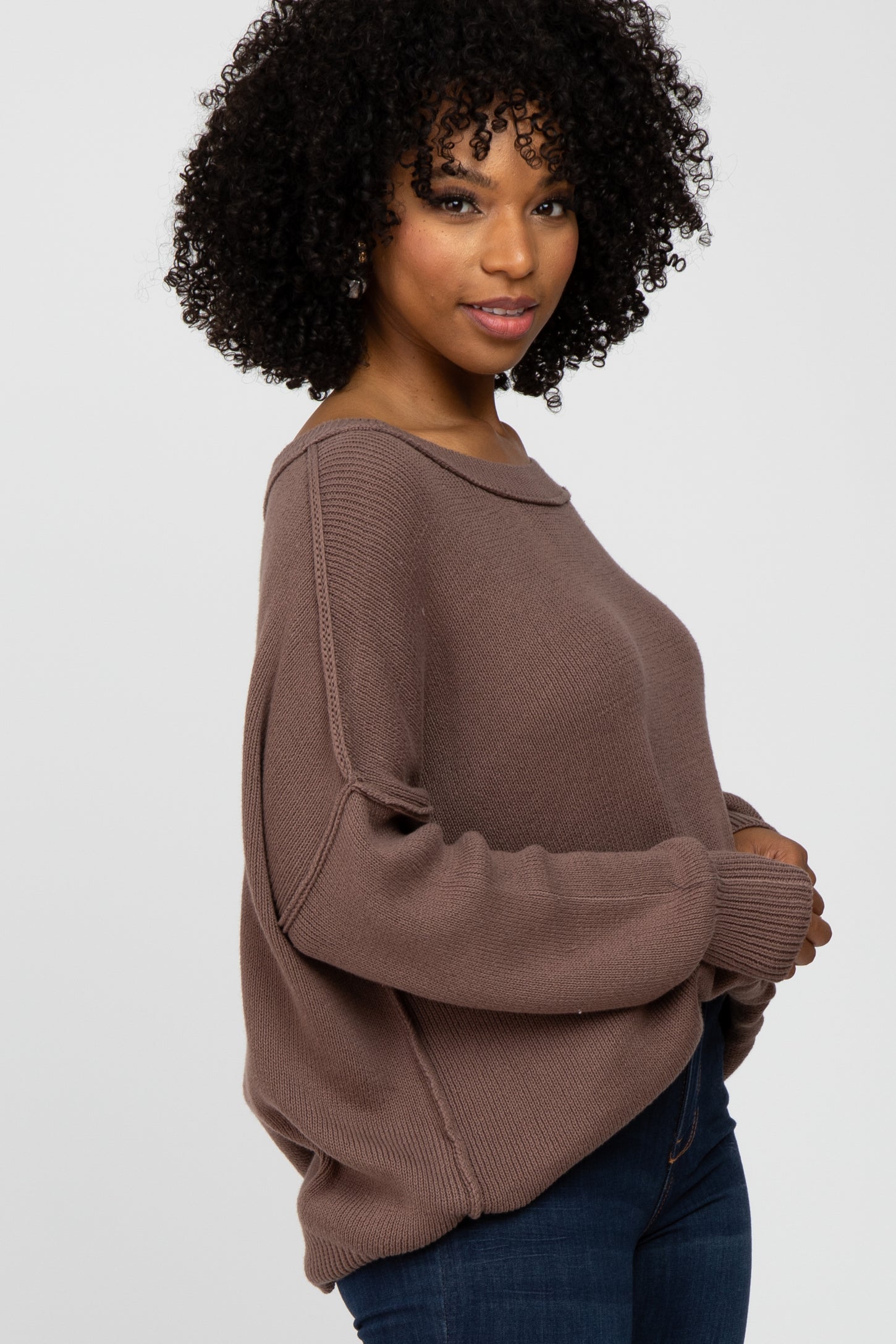 woman wearing a soft brown oversized sweater with a boat neckline and long sleeves