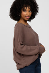 woman wearing a soft brown oversized sweater with a boat neckline and long sleeves