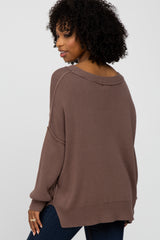 woman wearing a taupe oversized sweater with a scoop neck and side slits, shown from the back