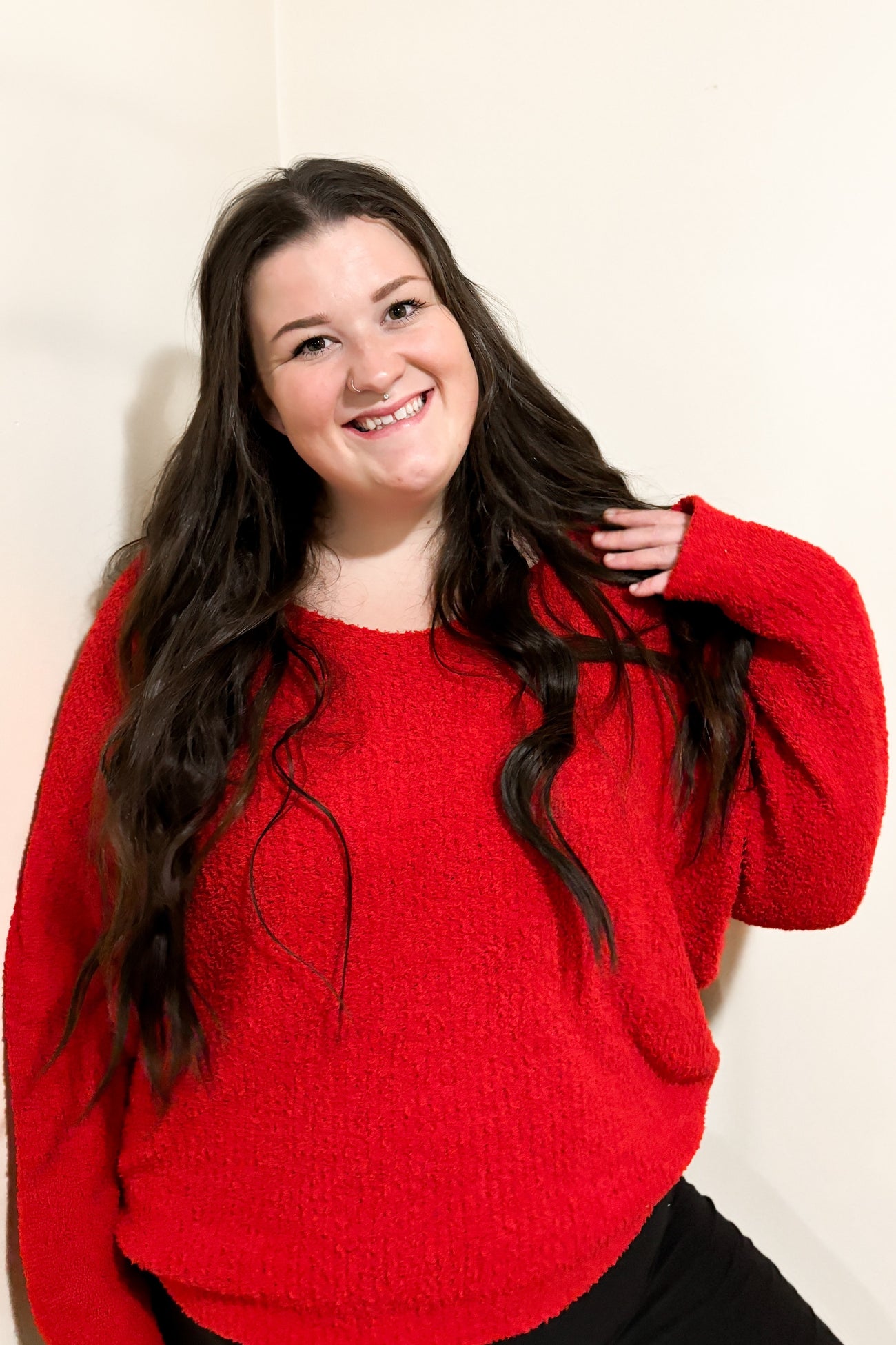 woman wearing a vibrant red oversized sweater with long sleeves and smiling at the camera