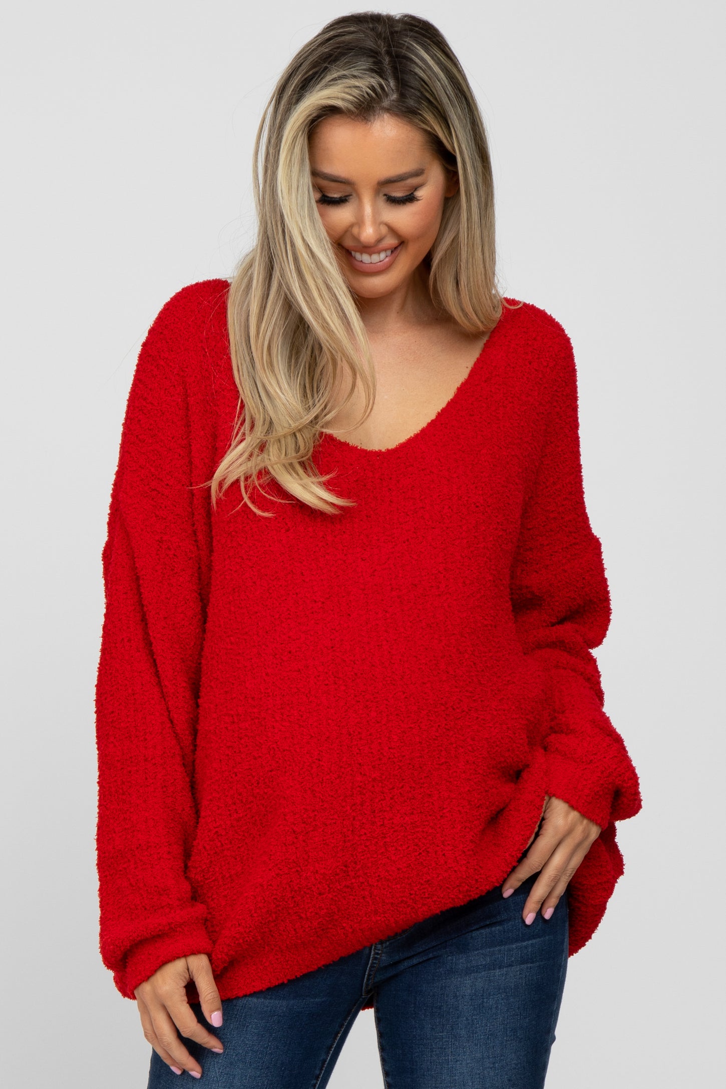 woman wearing a red oversized v-neck maternity sweater with long sleeves and a relaxed fit