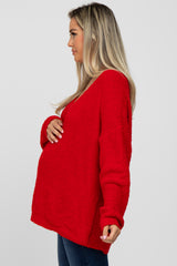 woman wearing a red fuzzy maternity sweater and holding her baby bump from the side