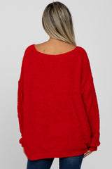 woman wearing a red oversized maternity sweater, seen from the back, with a relaxed fit and wide neckline