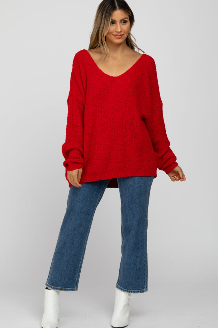 woman wearing a red oversized knit sweater with a v-neck and blue wide-leg jeans