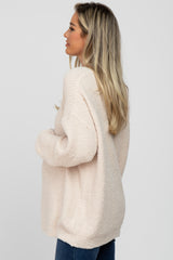 woman wearing a cozy light pink oversized maternity sweater with a relaxed fit and long sleeves