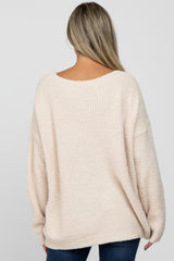 woman wearing a soft pink oversized maternity sweater with a scooped back and relaxed fit