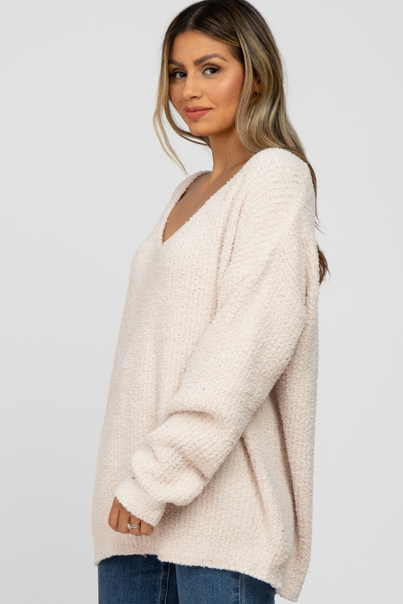 woman wearing a light pink oversized v-neck sweater with long sleeves and relaxed fit