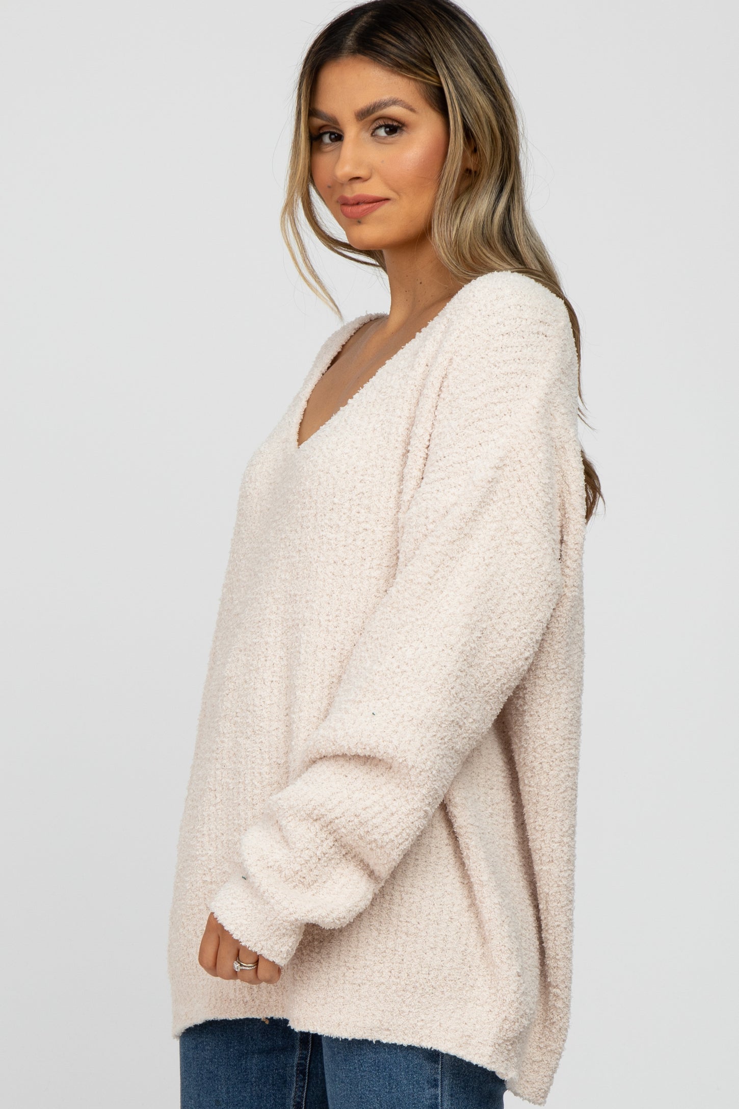 woman wearing a light pink oversized v-neck sweater with long sleeves and relaxed fit