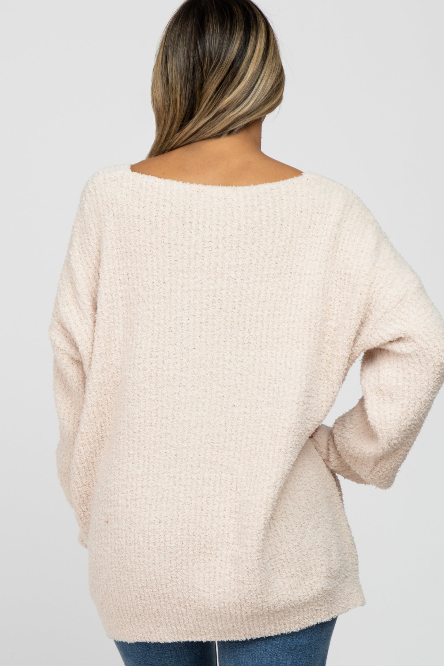 woman wearing a cozy light pink oversized sweater with a scoop back and long sleeves, shown from the back