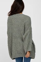 woman wearing a loose-fitting oversized gray cardigan with a textured knit pattern, showing the back view