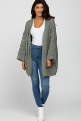 woman wearing a light gray textured open cardigan over a white top and high-waisted skinny jeans