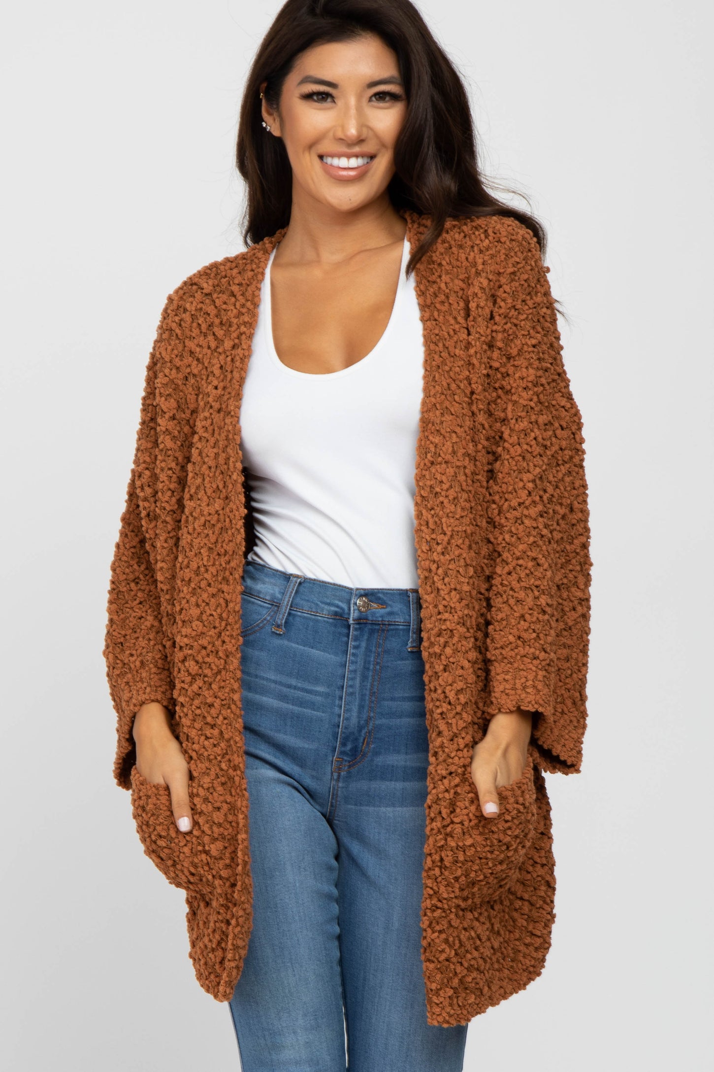 woman wearing an oversized rust-colored fuzzy cardigan over a white top and blue jeans