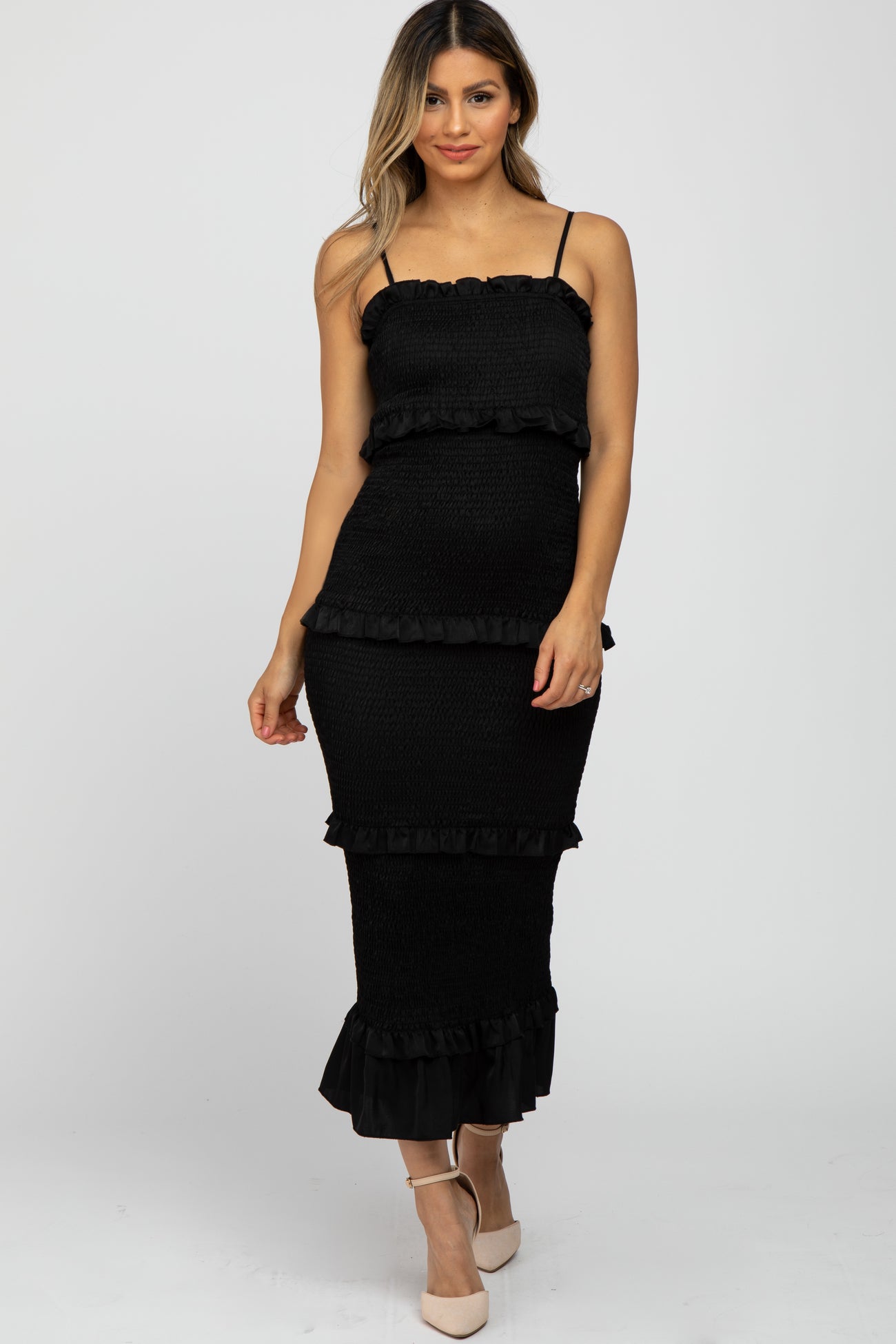 woman wearing a black smocked tiered maternity midi dress with ruffle trim and spaghetti straps