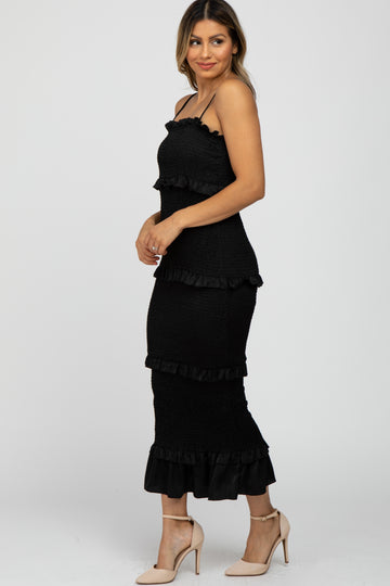 woman wearing a black tiered strapless dress with ruffle details and paired with nude high heels